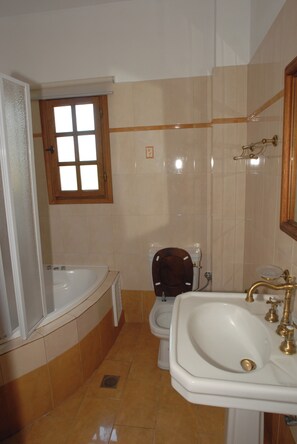 Ein Badezimmer mit Badewanne, Toilette, Waschbecken und einem Fenster.