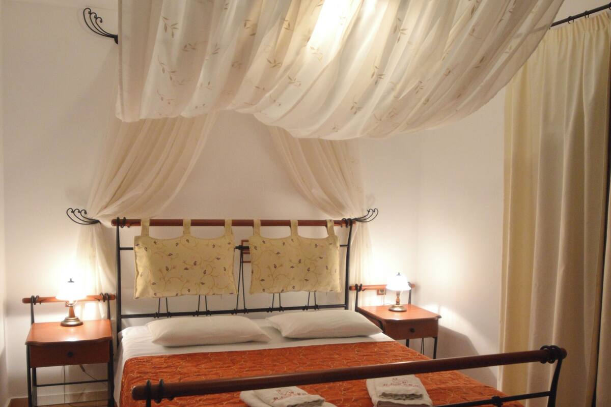 Ein Bett mit Baldachin, zwei Nachttische und ein Beistelltisch.