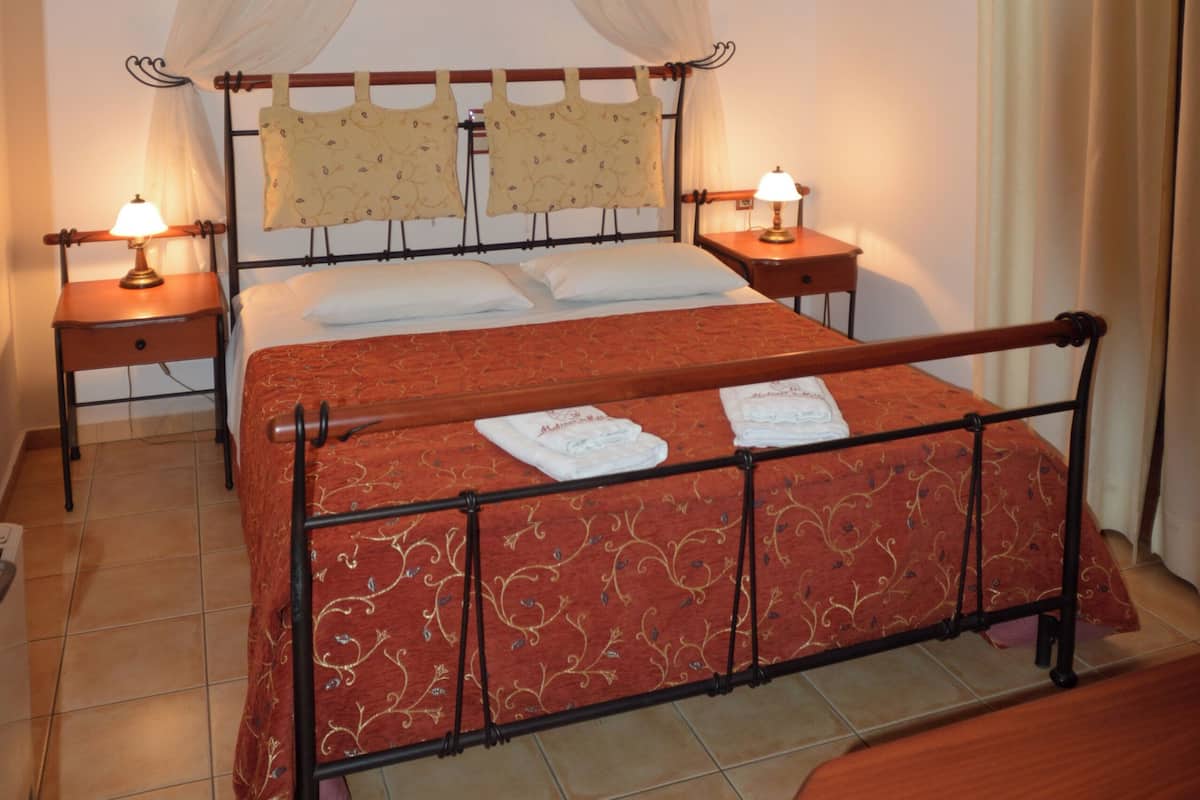 Ein Zimmer mit einem Bett, zwei Nachttischen, einer Sitzbank und einem Baldachinvorhang.