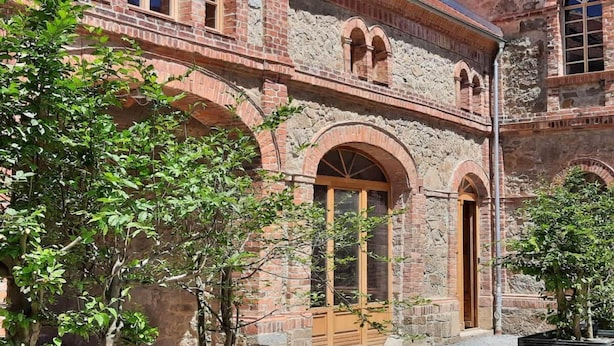 A historic building with arched windows and doors, stone walls, and a courtyard with trees. - Tiny House an Zwei Naturteichen - Ruhe, Kamin & Terrasse Nahe Dresden - Best Price! (Grossharthau)