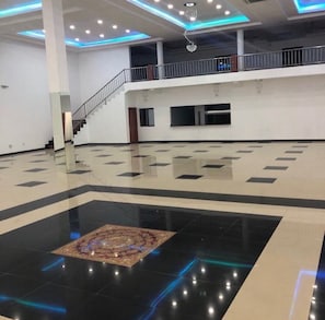 A spacious hall with a central carpeted area, a staircase, and a balcony.