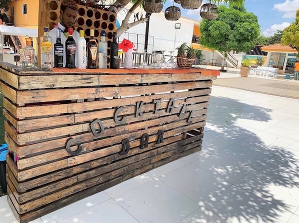 A wooden bar with the name 'COCKTAIL BAR' and various bottles on top.
