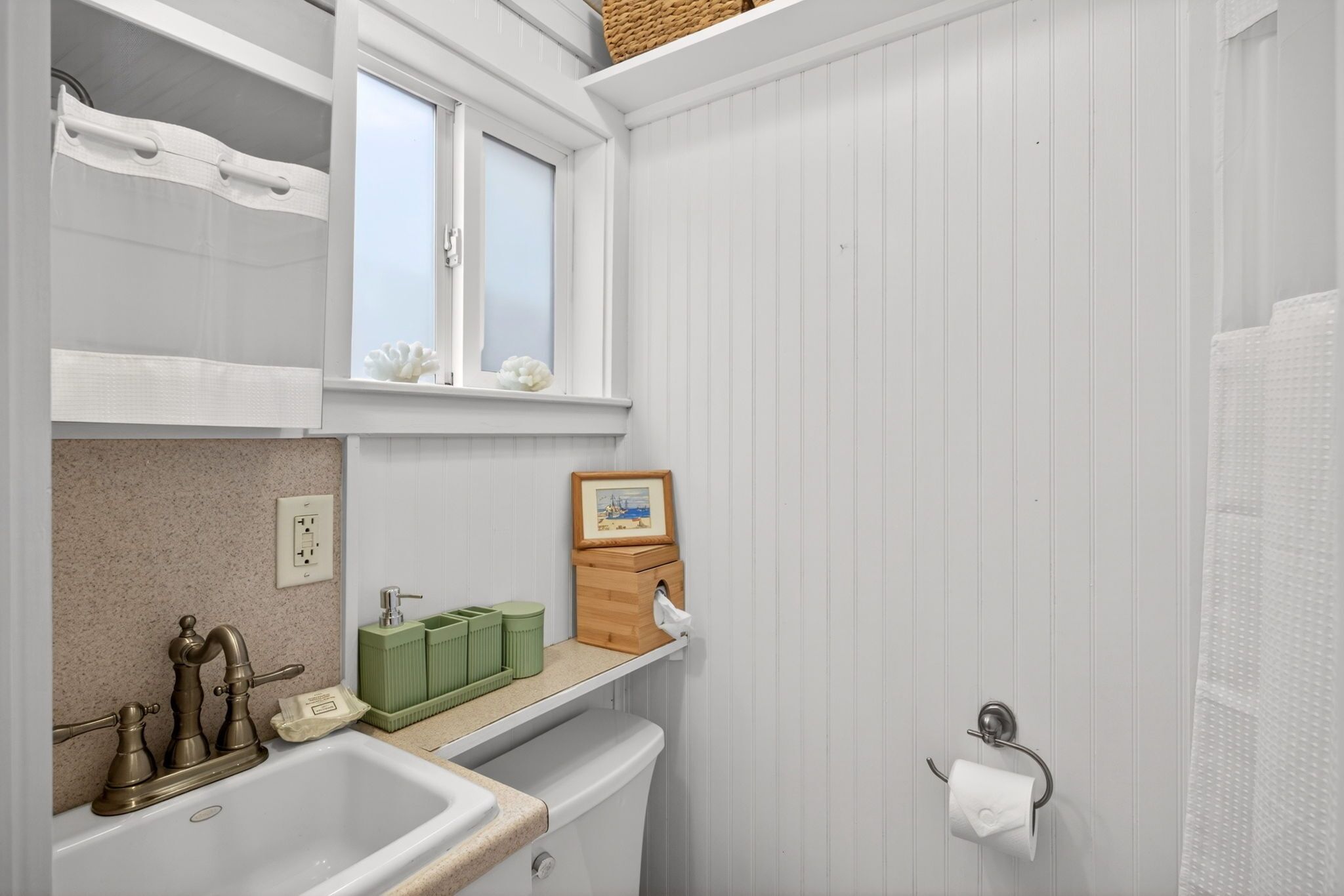 A bathroom with a sink, window, towel rack, and a picture frame on the wall.