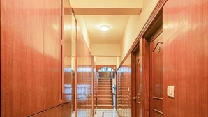 Ein Korridor mit Holztüren, einem Marmorboden und einer Treppe, die zu einer oberen Etage führt.