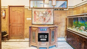 Ein Empfangsschalter mit einem 'HOTEL'-Schild, einer Uhr, einem gerahmten Zertifikat und einem Aquarium.