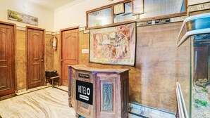 Ein Empfangsbereich mit einem Schild 'HOTEL', einer Kasse, Holztüren, einem Feuerlöscher und einem Wanddekor.