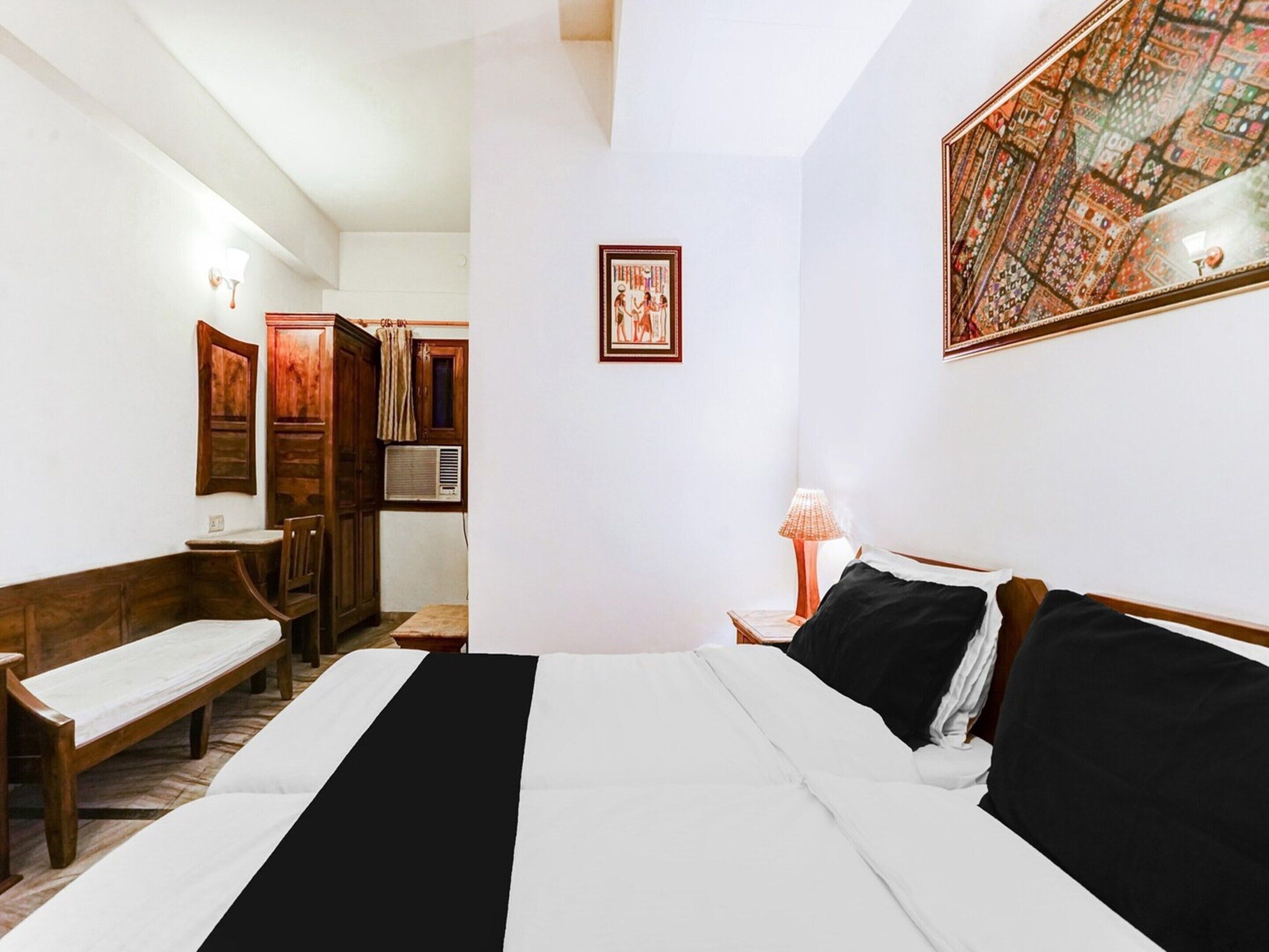 Ein Hotelzimmer mit einem Bett, einem Schreibtisch, einem Stuhl, einer Lampe und einem gerahmten Bild an der Wand.