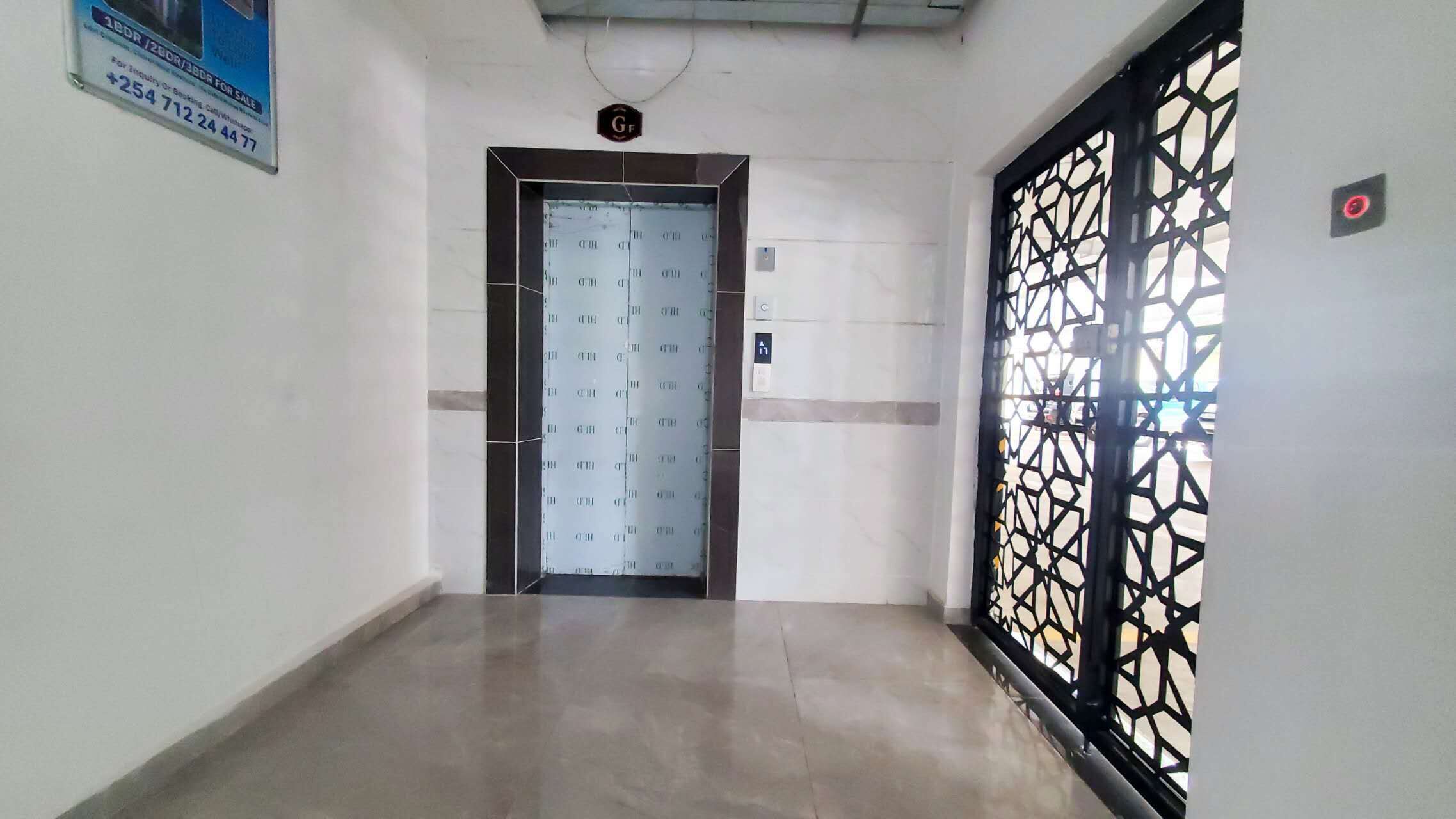 Un pasillo con una puerta, un papel tapiz estampado y un portón decorativo.