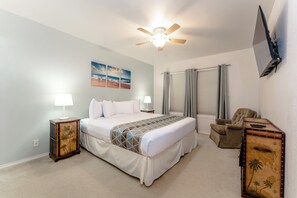 A neatly arranged bedroom with a bed, bedside lamps, a ceiling fan, a chair, and a wall-mounted TV. - Sand Dollar Retreat - private pool;short walk to beach;sleeps 10 (South Padre Island)