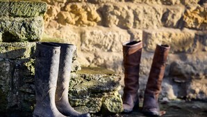 Un par de botas apoyadas contra una pared de piedra.