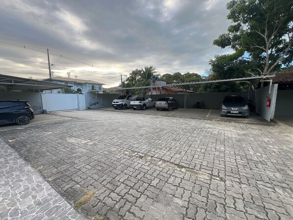 A paved parking area with several cars, a white gate, and a red fire extinguisher.
