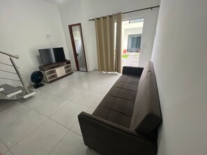 Ein Wohnzimmer mit einer Couch, einem Fernseher und einem Ventilator.