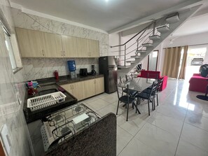 Eine moderne Küche mit Marmorfliesenspiegel, ein Essbereich mit Glastisch und eine Treppe, die in eine weitere Ebene führt.