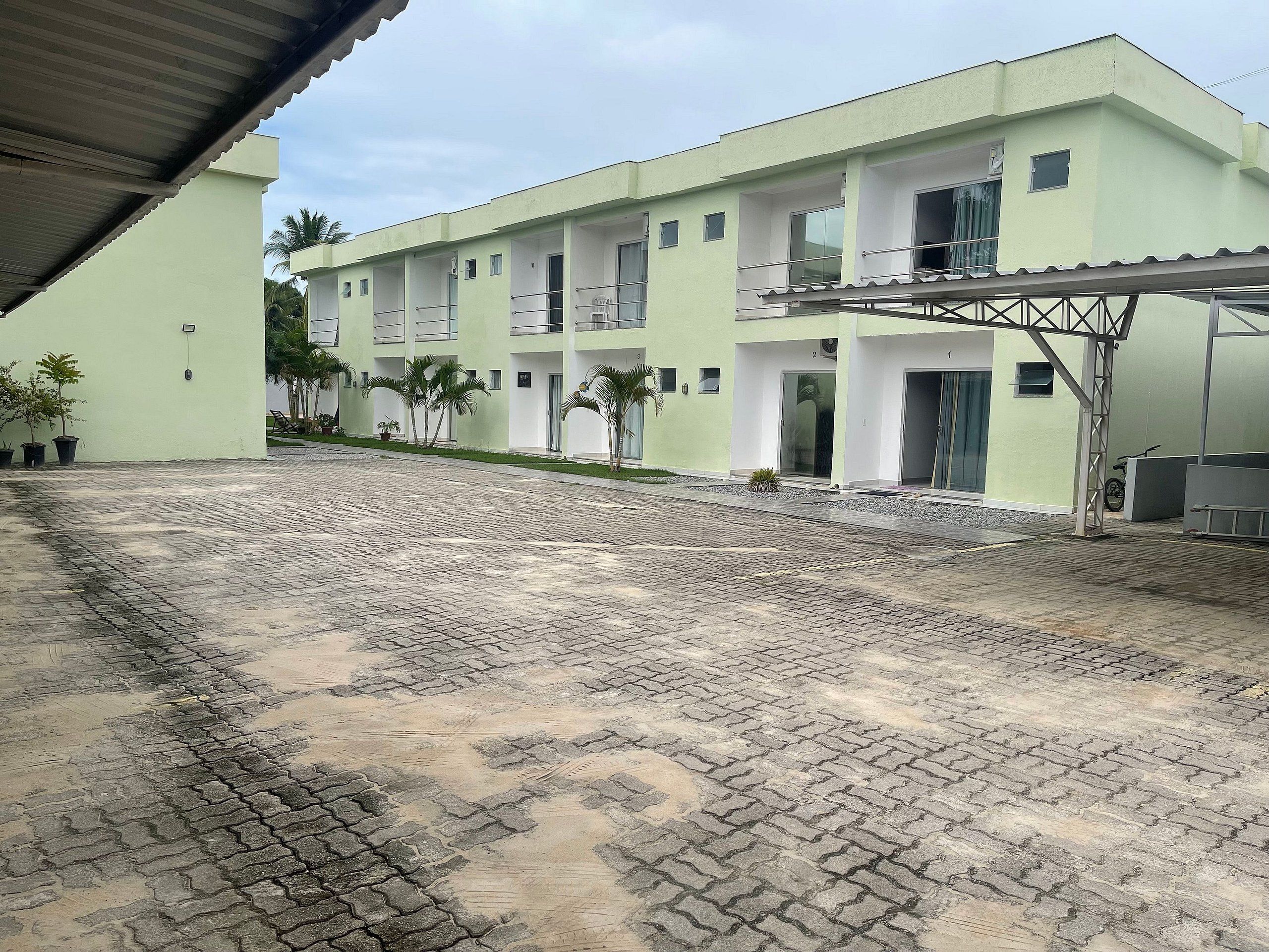 Un edificio con varios balcones, un patio empedrado y macetas con plantas.