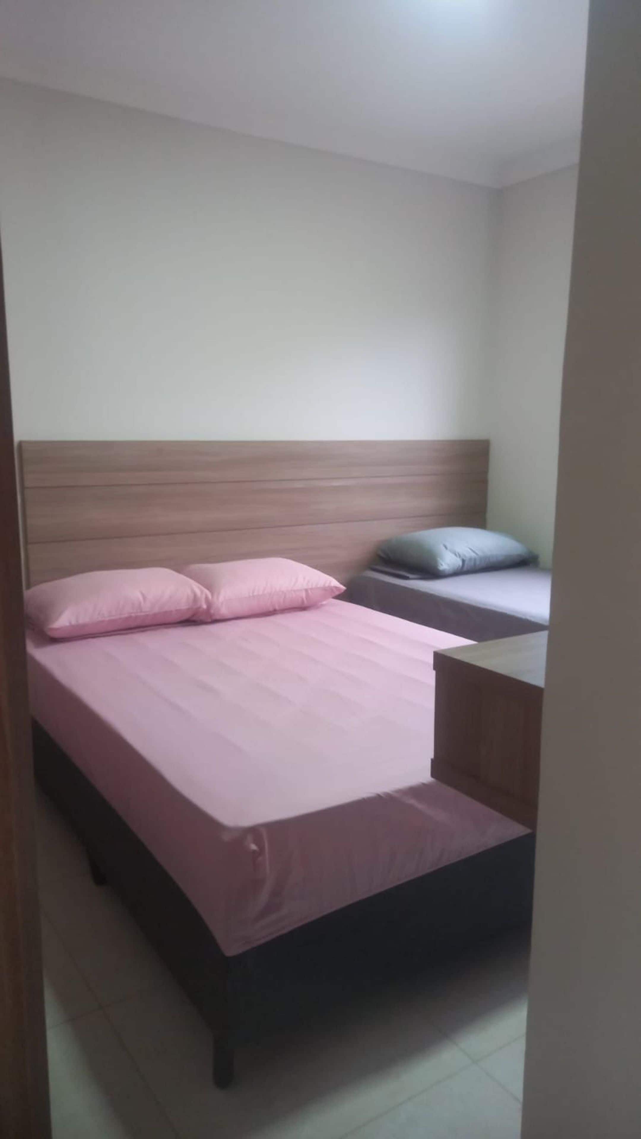Uma cama de solteiro com cabeceira de madeira, mesa de cabeceira e um travesseiro.