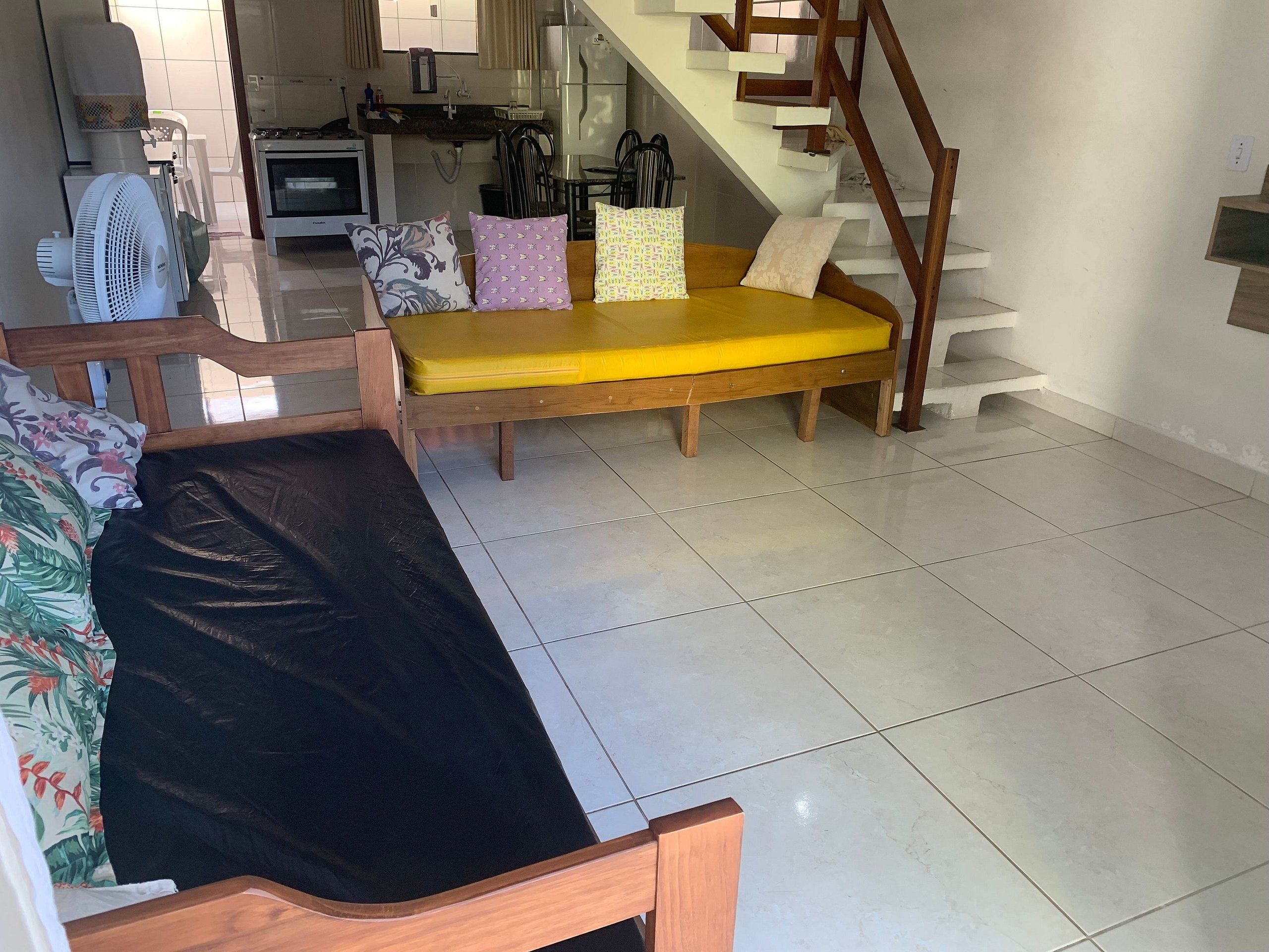 A living area with a sofa, a bench, a staircase, and a kitchen in the background.