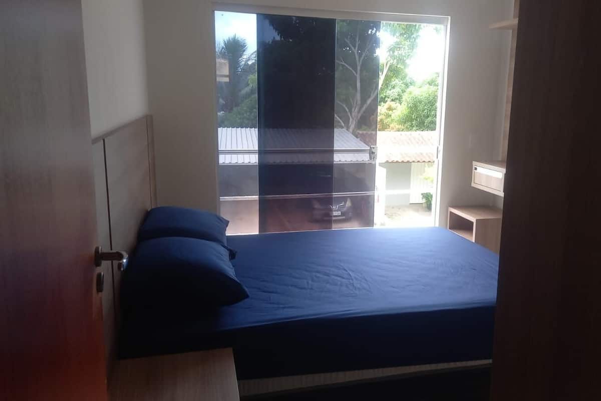 Un dormitorio con cama, ventana y vista al exterior.