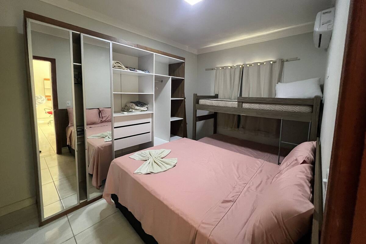 Un dormitorio con una cama litera, un armario con puertas de espejo y una mesita de noche.