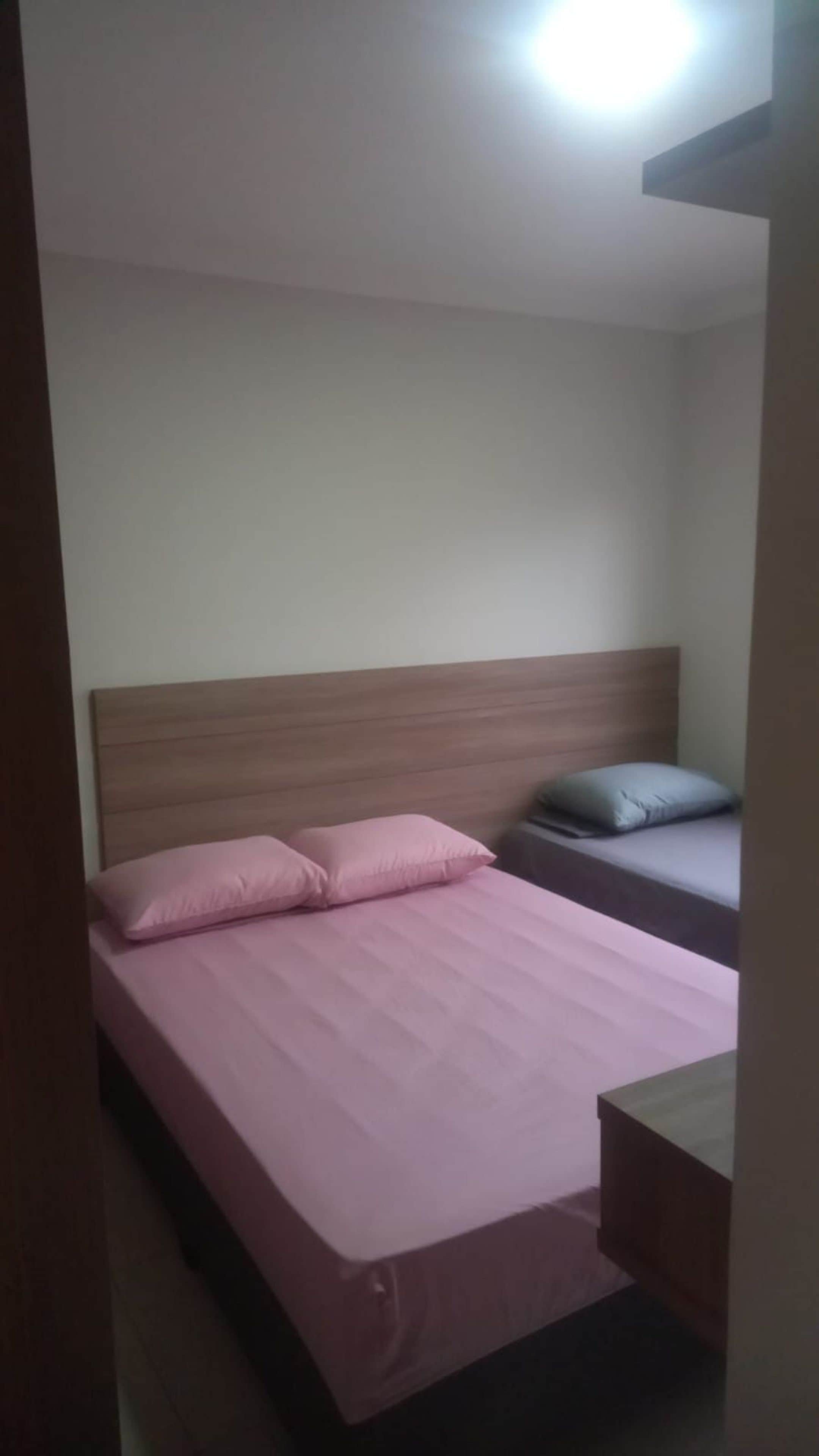Uma cama de solteiro com cabeceira de madeira, mesa de cabeceira e criado-mudo.