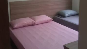 Uma cama de solteiro com cabeceira de madeira, mesa de cabeceira e criado-mudo.