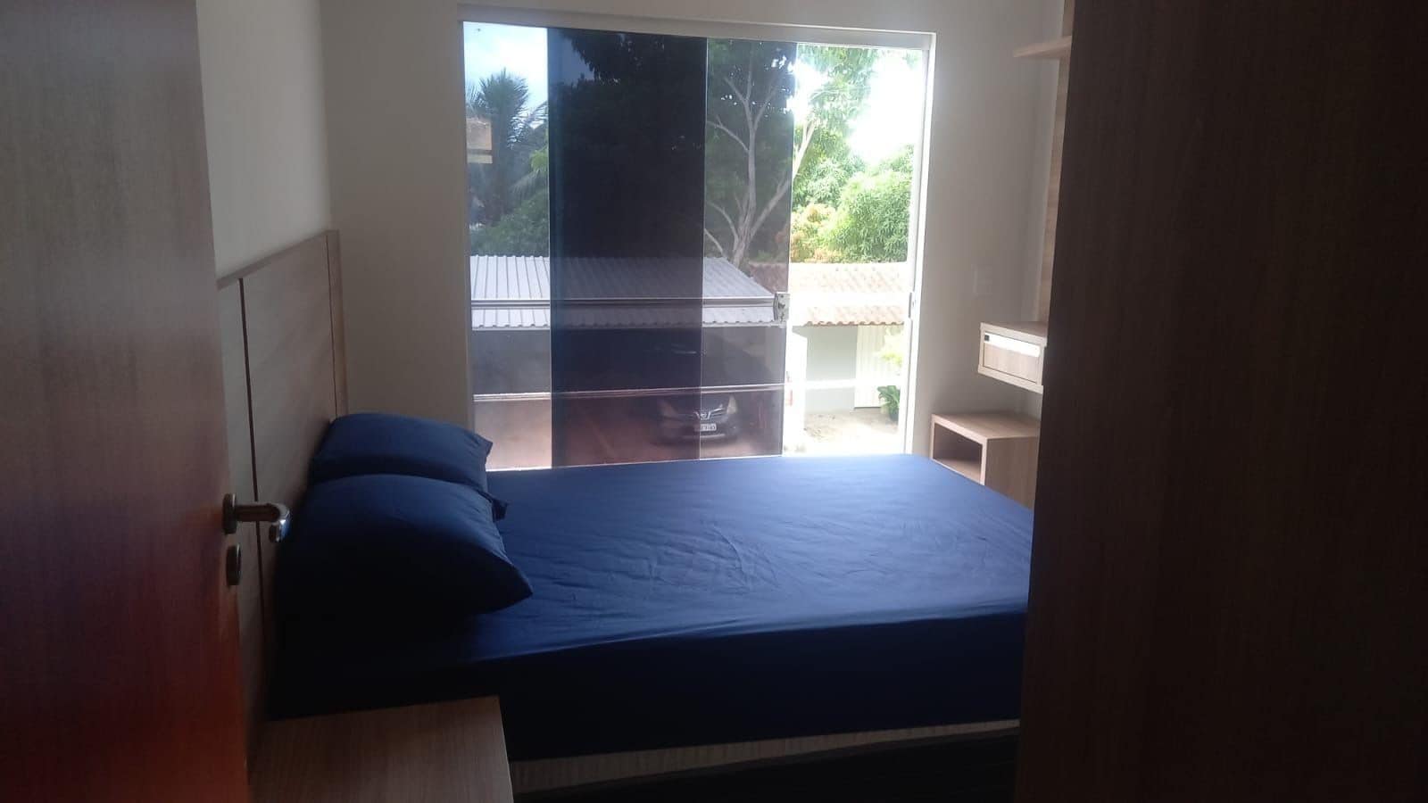 A bedroom with a bed, a window, and a view of the outside.