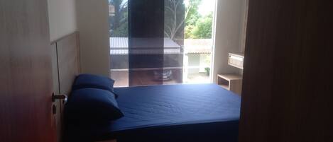 A bedroom with a bed, a window, and a view of the outside.