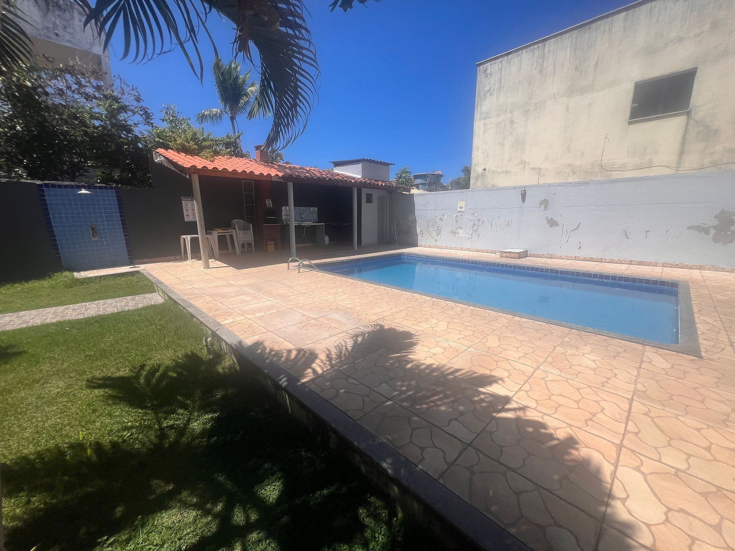 Une piscine dont les bords sont recouverts de carreaux, entourée d’une terrasse dallée.