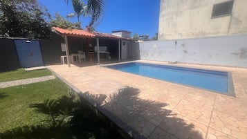 Une piscine dont les bords sont recouverts de carreaux, entourée d’une terrasse dallée.