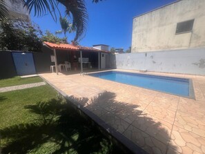 Una piscina con bordes azulejados, rodeada de un patio empedrado.