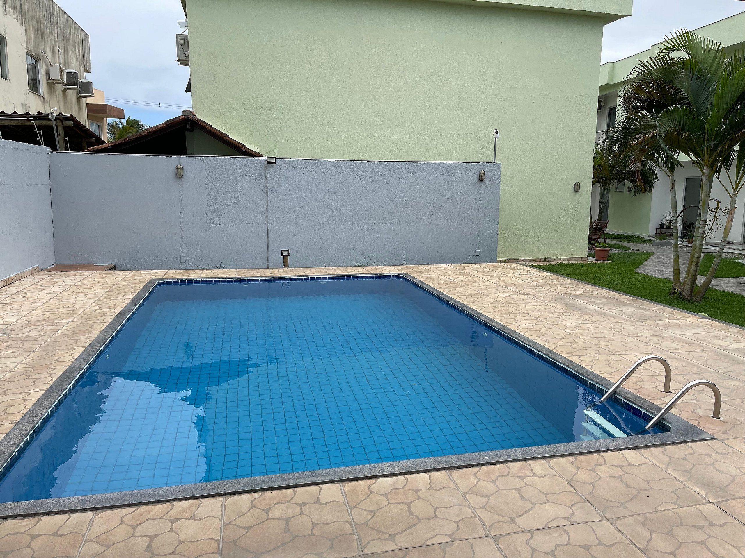 Una piscina rectangular con bordes de azulejos, rodeada por un patio de piedra con diseños.
