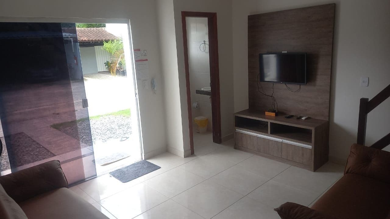 A living room with a TV, a wooden entertainment unit, a door leading outside, and a staircase.
