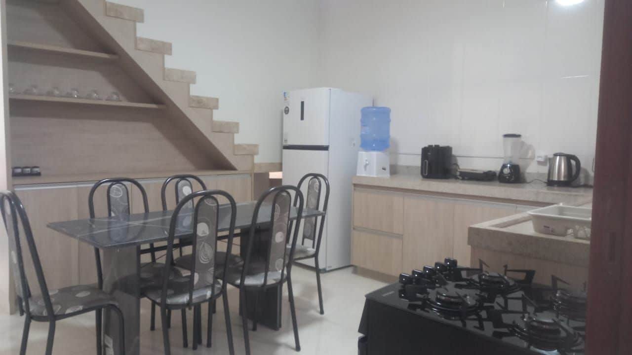 Une cuisine compacte équipée d’un réfrigérateur, d’un distributeur d’eau, d’une machine à café et d’une cuisinière à gaz.