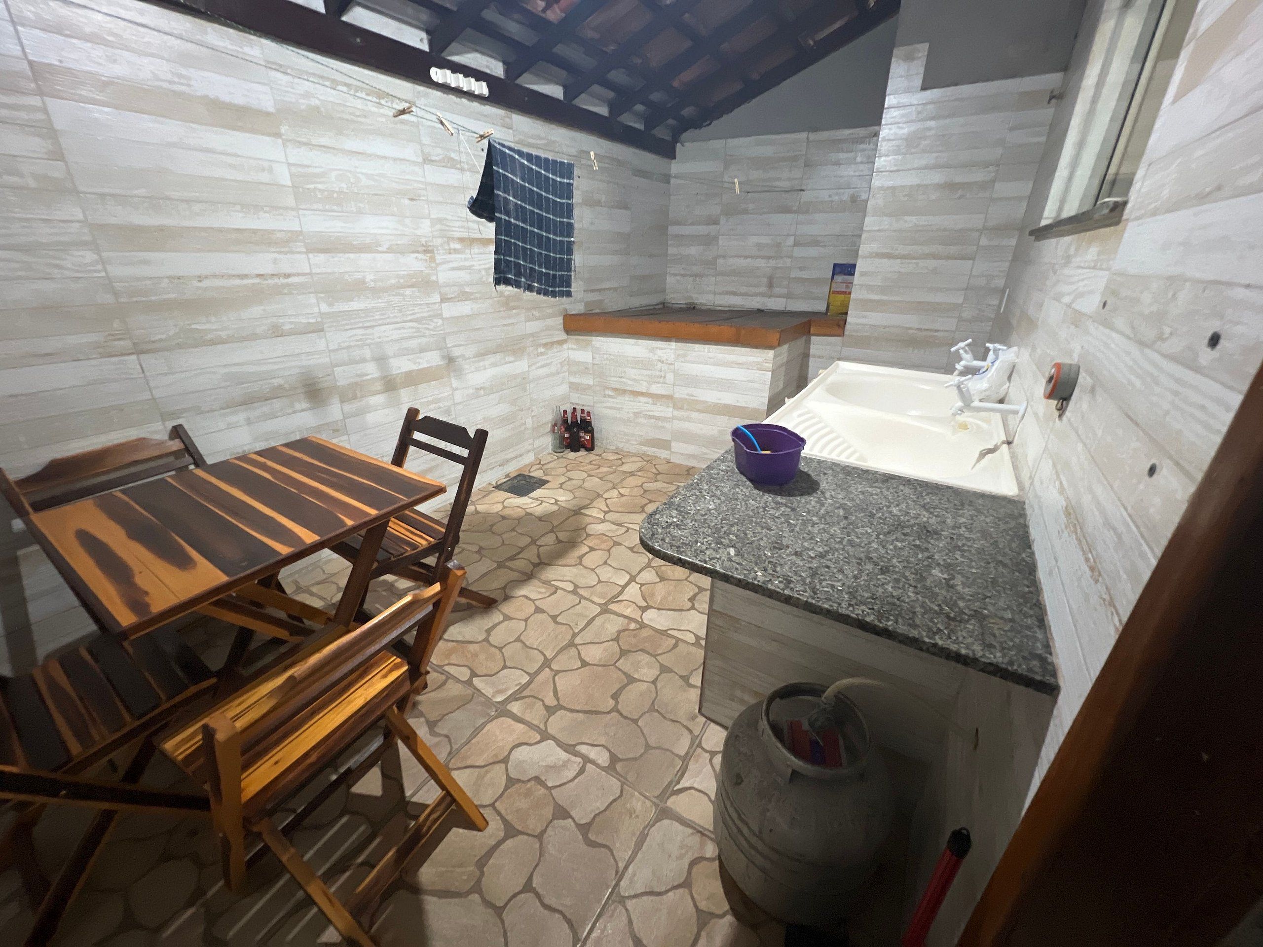 A compact kitchen with a dining table, chairs, a sink, and a tiled floor.