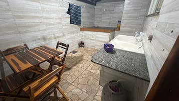 A compact kitchen with a dining table, chairs, a sink, and a tiled floor.