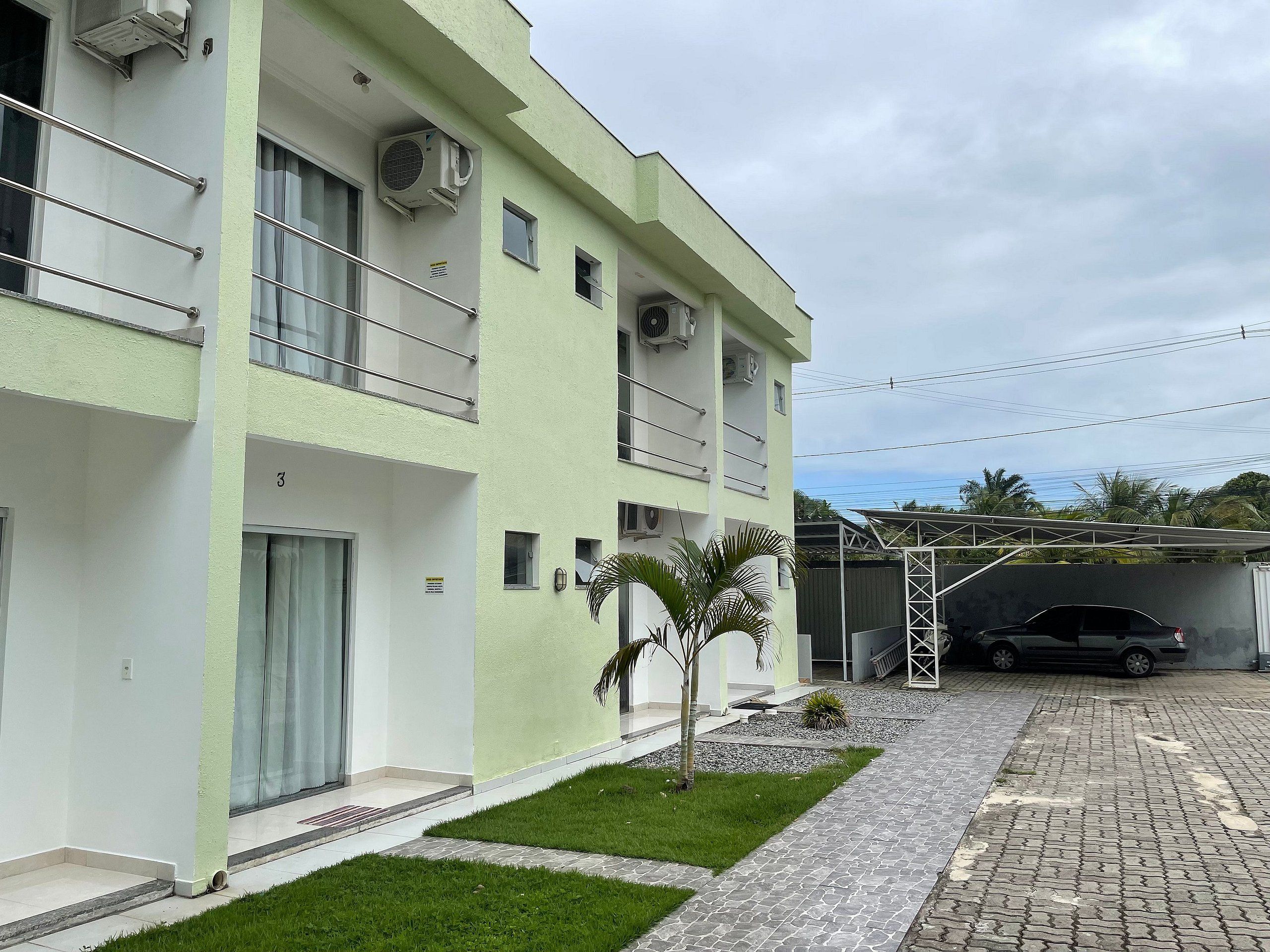 A multi-story building with balconies, air conditioning units, and a paved driveway.