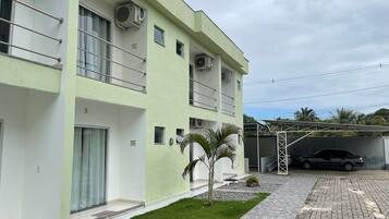 A multi-story building with balconies, air conditioning units, and a paved driveway.