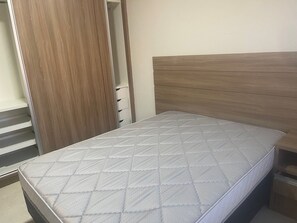 Ein Schlafzimmer mit einem Bett, einem Holzschrank und einem eingebauten Regal.