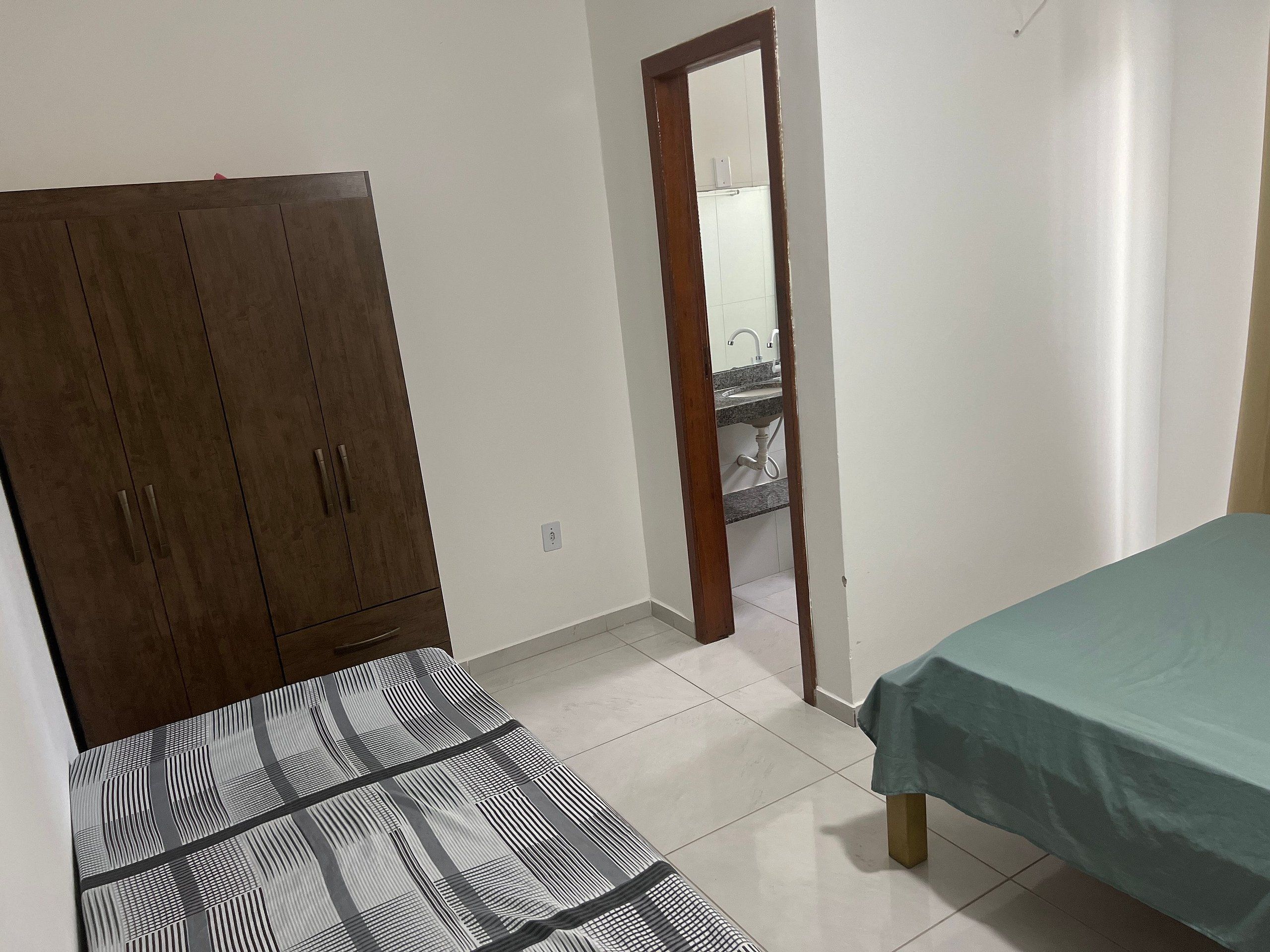 A bedroom with a bed, a wardrobe, and a bathroom visible through a door.