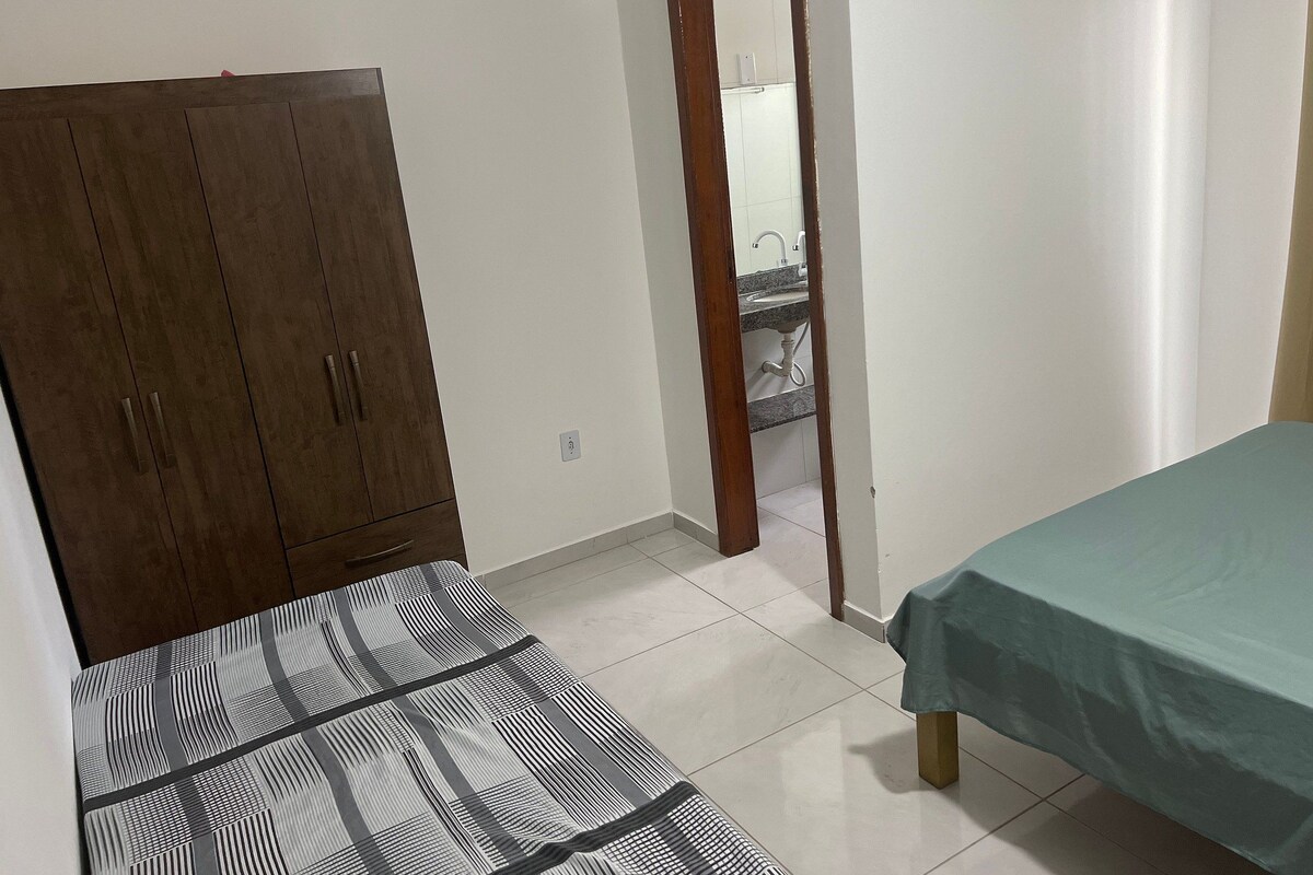 Ein Schlafzimmer mit Bett, Kleiderschrank und angrenzendem Badezimmer.