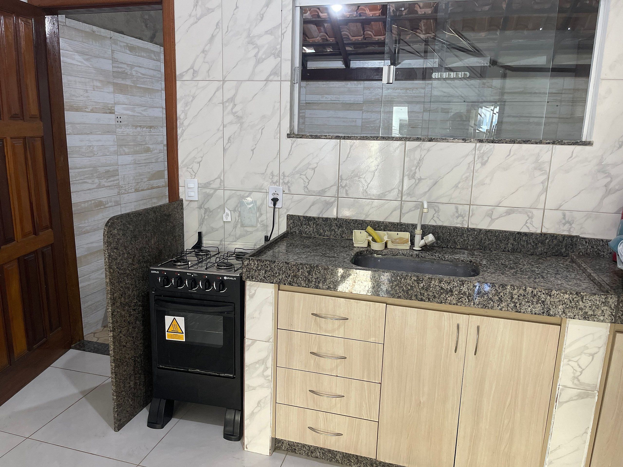 Una cocina con estufa a gas, encimera de granito, gabinetes de madera y salpicadero de azulejos.