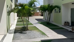 A courtyard with a paved walkway, palm trees, and buildings with balconies.