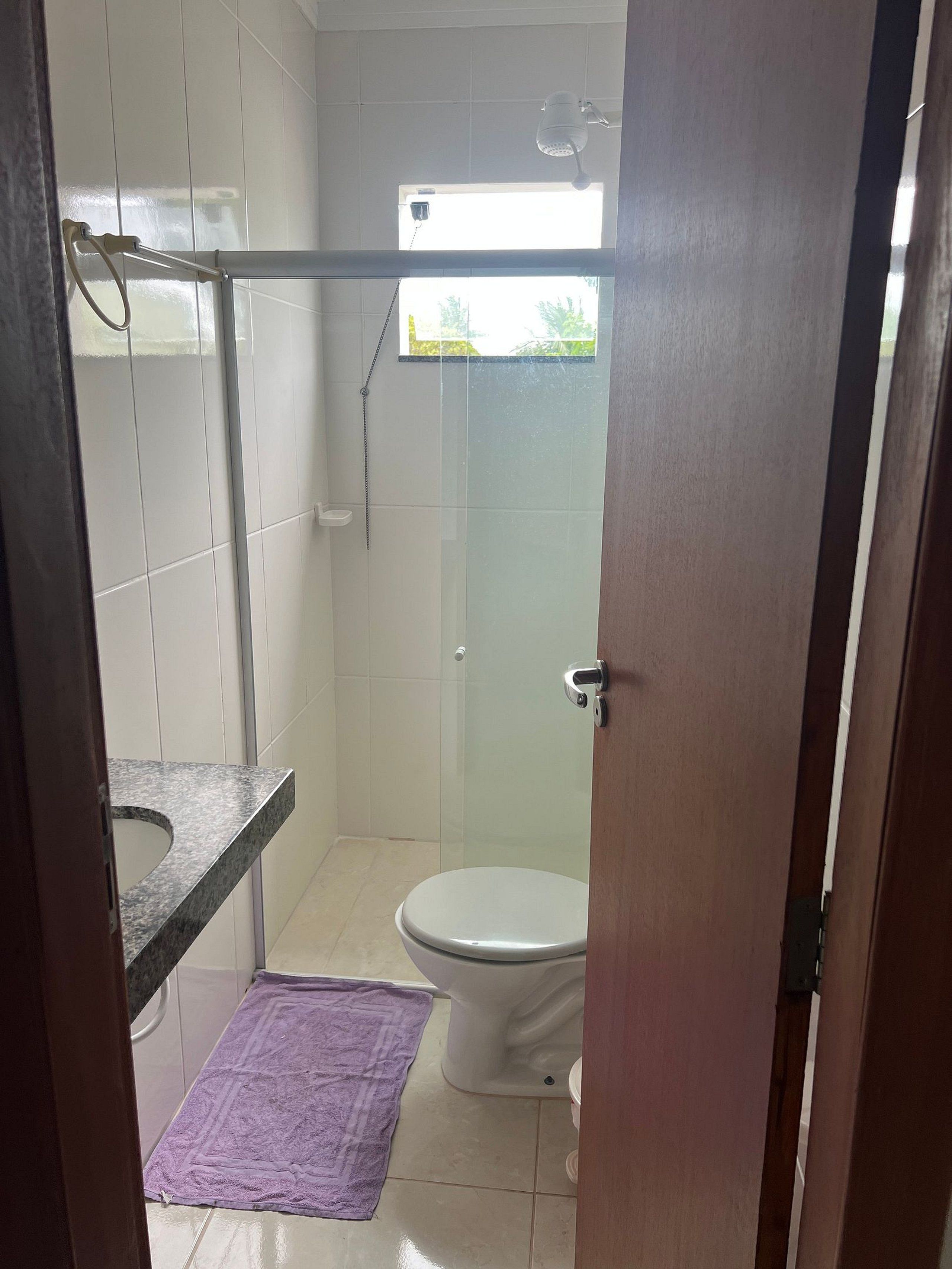 A bathroom with a shower, toilet, and a towel on the floor.