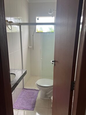 Ein Badezimmer mit Dusche, Toilette und einem Handtuch auf dem Boden.