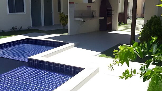 A modern outdoor pool area with a pergola, a barbecue grill, and a small garden.