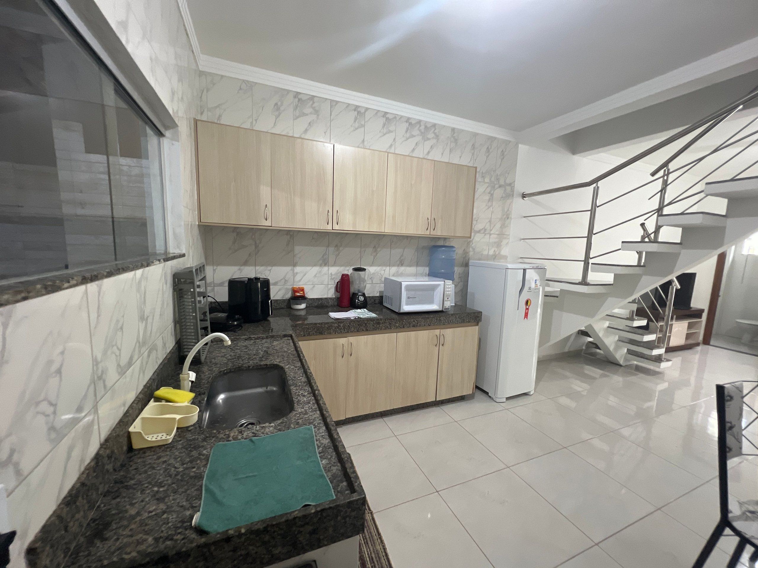 A modern kitchen with marble backsplash, wooden cabinets, granite countertop, stainless steel sink, and a built-in microwave.