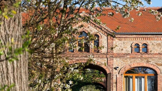 A brick building with a large arched entrance, a wooden door, and a pathway leading through it. - Tiny House mit Terrasse, Grill & Kamin Direkt am Naturteich - Best Price! (Grossharthau)