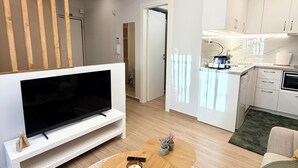 Moderni olohuone, jossa on litteänäyttöinen televisio, puinen sohvapöytä ja pyöreä matto.