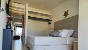 A bedroom with a bed, a headboard, a wall-mounted light, and a decorative wall piece. - Mat Suites (rhodes)