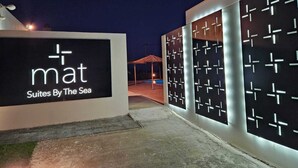 A modern building with a sign reading 'mat Suites By The Sea' and a series of illuminated panels with geometric patterns. - Mat Suites (rhodes)
