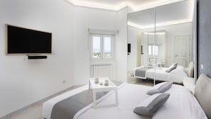 A modern hotel room with a bed, bedside table, and a large mirror reflecting the room.